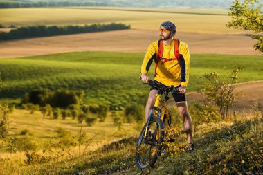 Genç adam kırsal bir yolda Bisiklete binme