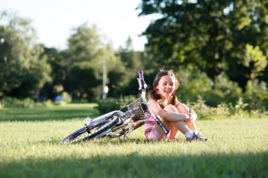 Onun Bisiklet yeşil çim üzerinde yakın oturan küçük kız.