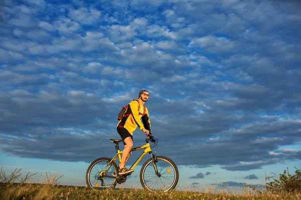 Молодий чоловік їде на велосипеді по сільській дорозі — стокове фото