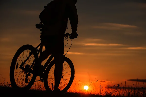 Silhuetten av en cykel på himmel bakgrund under solnedgången — Stockfoto