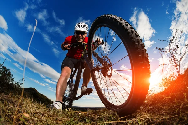 Ciclista montar en bicicleta de montaña en el camino rocoso al amanecer —  Fotos de Stock