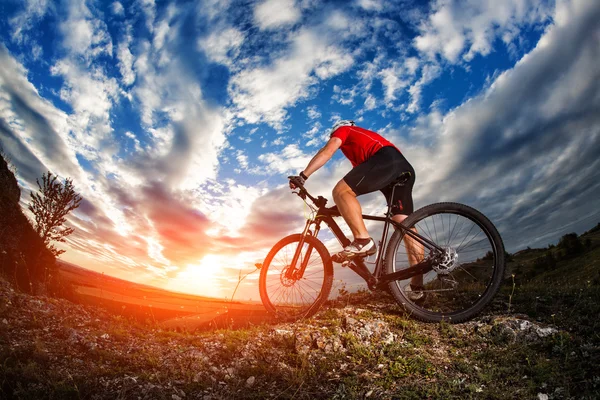 Fietser paardrijden mountainbike op rotsachtige trail bij zonsopgang — Stockfoto