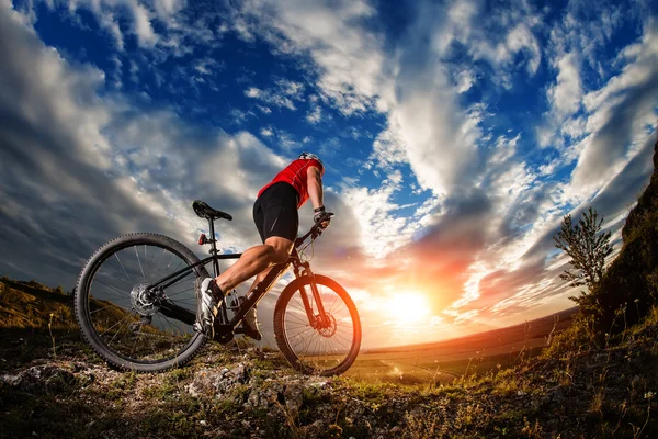 Radler fährt Mountainbike auf felsigem Weg bei Sonnenaufgang — Stockfoto