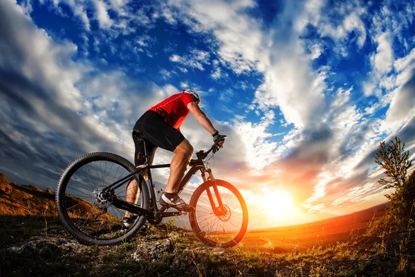 Ciclista de pé com mountain bike na trilha ao pôr do sol — Fotografia de Stock