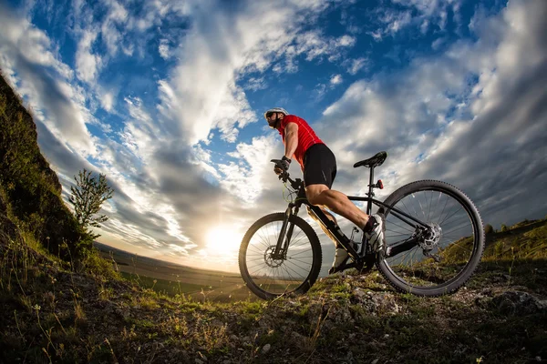 Велосипедист стоит с горным велосипедом на тропе на закате — стоковое фото