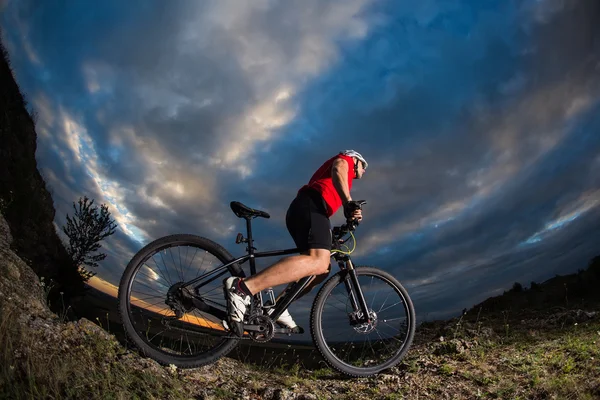 Ποδηλάτης στέκεται με ποδήλατο βουνού μονοπάτι στο ηλιοβασίλεμα — Φωτογραφία Αρχείου