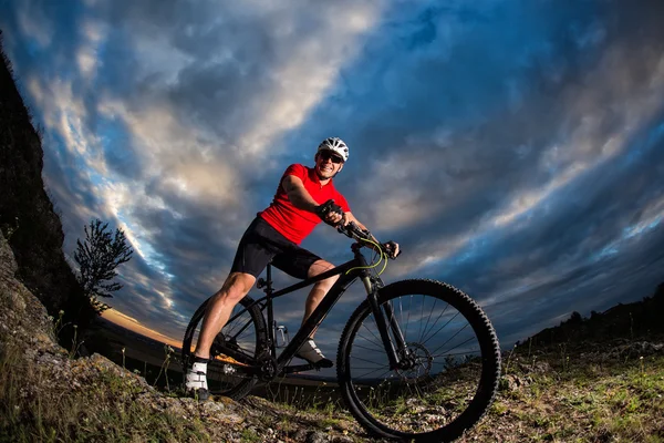 Велосипедист стоит с горным велосипедом на тропе на закате — стоковое фото