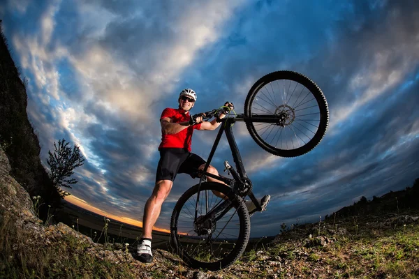 Rowerzysta, stojąc z rowerów górskich na szlak o zachodzie słońca — Zdjęcie stockowe