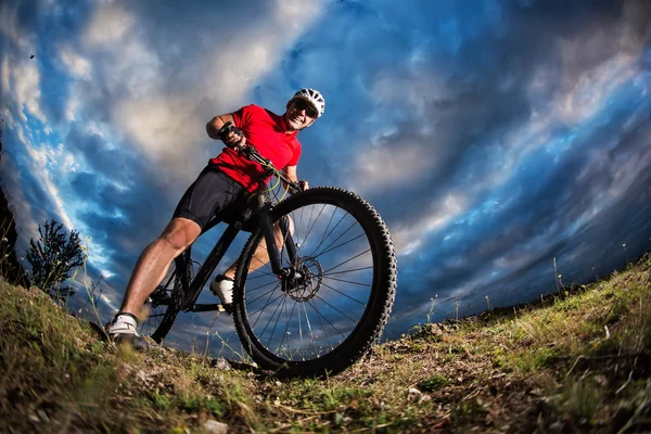 Fietser permanent met mountainbike op spoor bij zonsondergang — Stockfoto