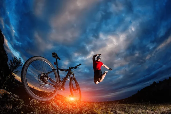 Ciclista de pé com mountain bike na trilha ao pôr do sol — Fotografia de Stock