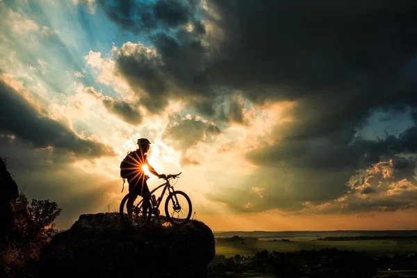 Silhueta de um motociclista e bicicleta no fundo do céu . — Fotografia de Stock