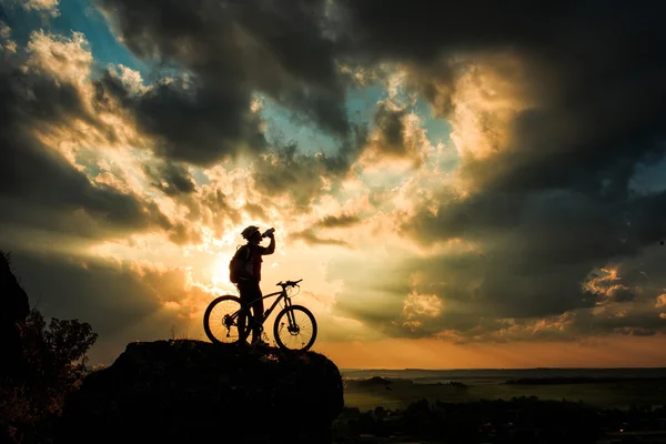 Silhouette of a biker and bicycle on sky background. — Stock Photo, Image