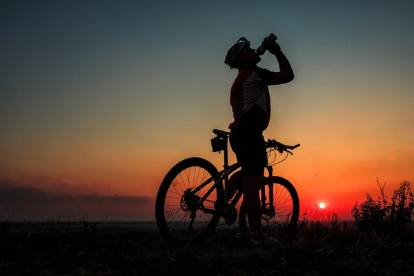 Σιλουέτα του ένα biker και το ποδήλατο σε φόντο του ουρανού. — Φωτογραφία Αρχείου