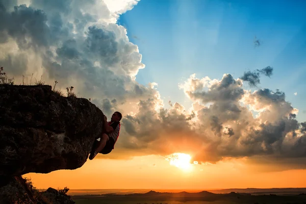 Een man zit op een rocknd op zoek bij zonsondergang — Stockfoto
