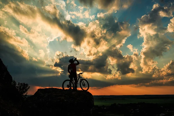 Silhouette eines Radfahrers und eines Fahrrads auf Himmelshintergrund. — Stockfoto