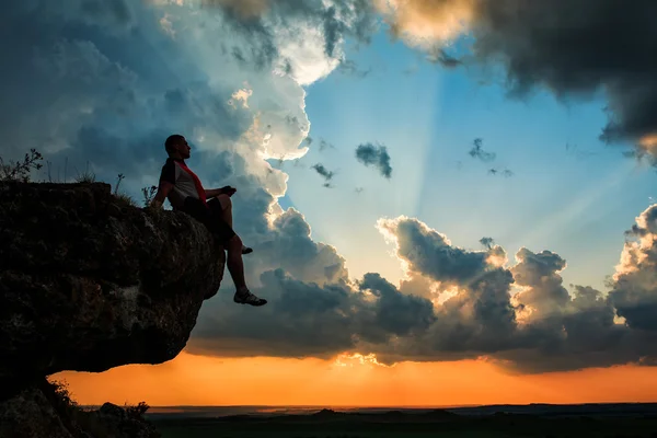 Hombre sentado en la cima de piedra de alta montaña — Foto de Stock