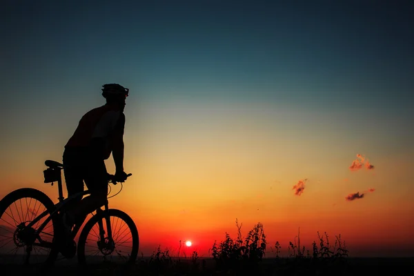 Silueta de un motorista y bicicleta en el fondo del cielo . — Foto de Stock