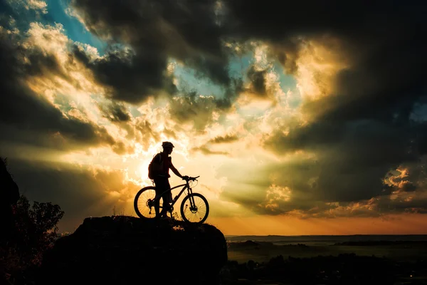Sziluettjét a biker és a kerékpár a háttérégbolt. — Stock Fotó