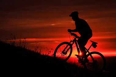 Silhouette bir motorcu ve gün batımı arka plan üzerinde bisiklet.