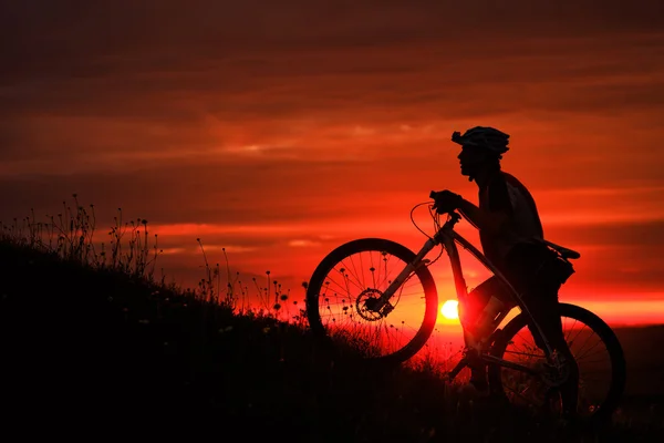 Silhouette eines Radfahrers und eines Fahrrads vor dem Hintergrund des Sonnenuntergangs. — Stockfoto
