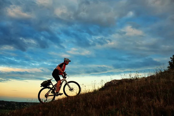 Silhouette bir motorcu ve gökyüzü arka plan üzerinde bisiklet. — Stok fotoğraf