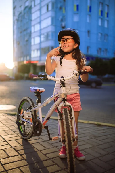 Niña con bicicleta en el parque de verano contra el atardecer —  Fotos de Stock