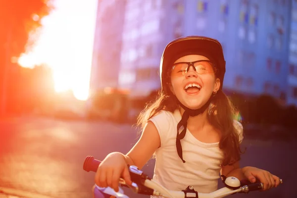 Lille pige med cykel i sommerparken mod solnedgang - Stock-foto