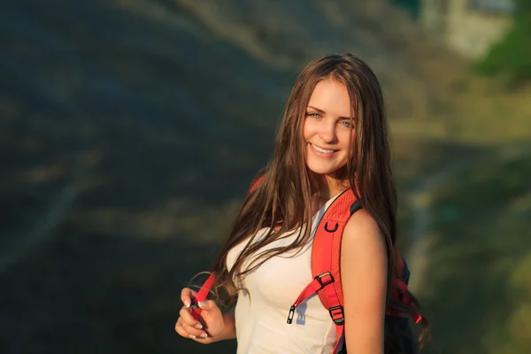 Mujer joven con mochila roja caminando en verano al atardecer . —  Fotos de Stock