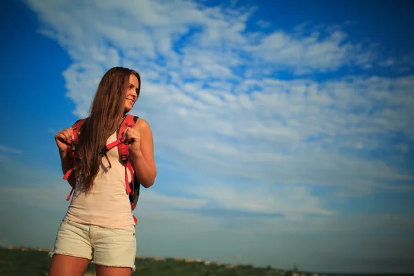 Mujer joven con mochila roja caminando en verano al atardecer . —  Fotos de Stock