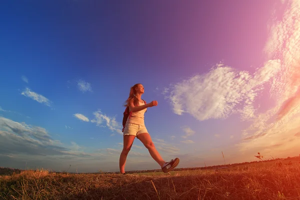 Mujer joven con mochila roja caminando en verano al atardecer . —  Fotos de Stock