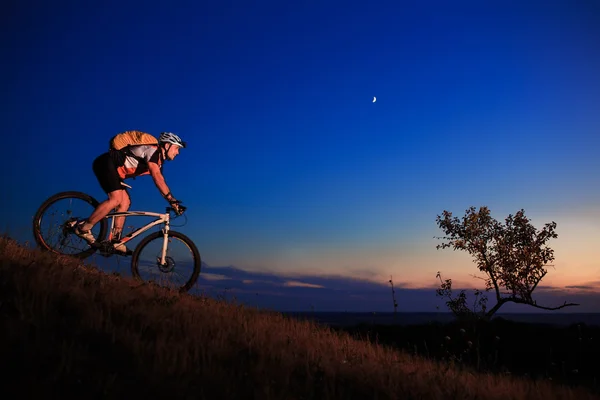 Silhouette eines Radfahrers und eines Fahrrads vor dem Hintergrund des Sonnenuntergangs. — Stockfoto