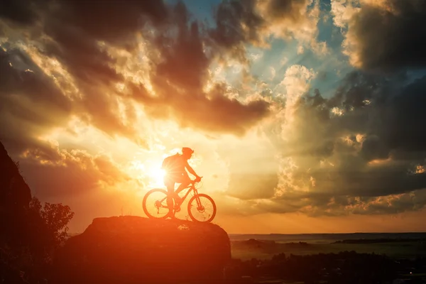 Silhueta de um motociclista e bicicleta no fundo do céu . — Fotografia de Stock