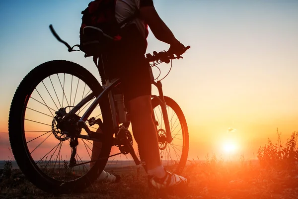 Silhueta de um motociclista e bicicleta no fundo do céu . — Fotografia de Stock