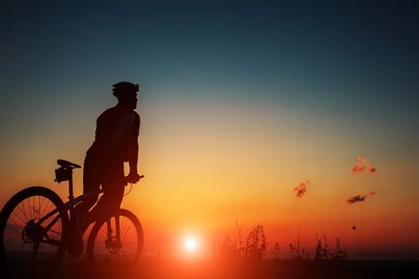 Silhouette d'un motard et vélo sur fond de ciel . — Photo