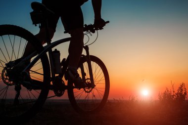 Silhouette bir motorcu ve gökyüzü arka plan üzerinde bisiklet.