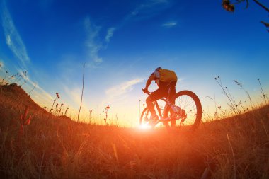 Silhouette bir motorcu ve gökyüzü arka plan üzerinde bisiklet.