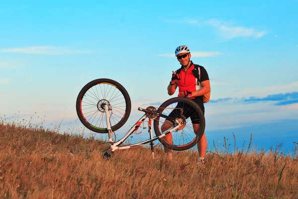 Rowerzysta mężczyzna naprawa rowerów przeciw błękitne niebo — Zdjęcie stockowe