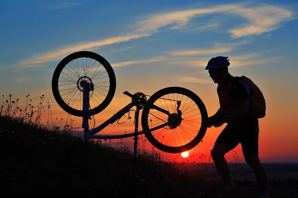 Sziluettjét férfi kerékpáros ellen sunset kerékpár javítás — Stock Fotó