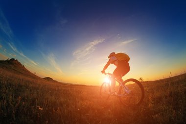 Silhouette bir motorcu ve gökyüzü arka plan üzerinde bisiklet.