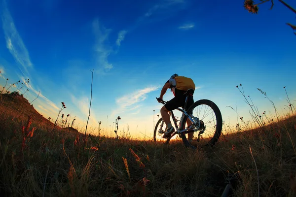 Silhueta de um motociclista e bicicleta no fundo do céu . — Fotografia de Stock