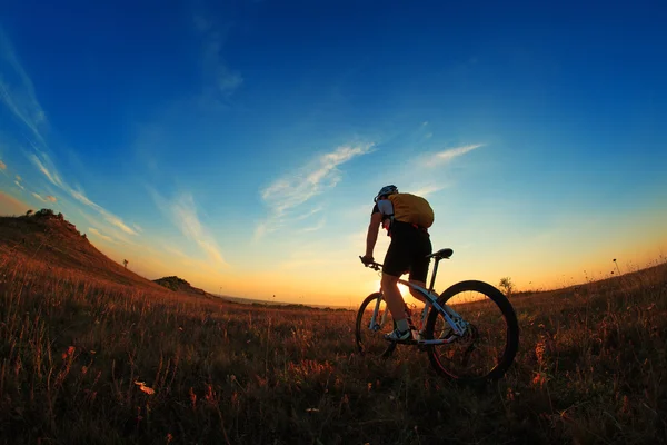 Silhueta de um motociclista e bicicleta no fundo do céu . — Fotografia de Stock