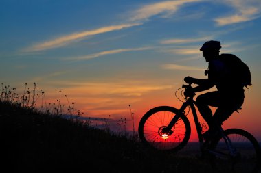 Silhouette bir motorcu ve gökyüzü arka plan üzerinde bisiklet.