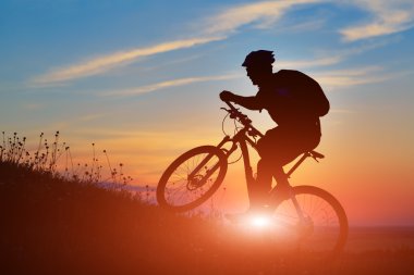 Silhouette bir motorcu ve gökyüzü arka plan üzerinde bisiklet.