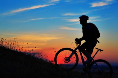 Silhouette bir motorcu ve gökyüzü arka plan üzerinde bisiklet.