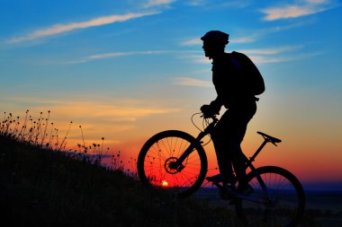 Silhouette bir motorcu ve gökyüzü arka plan üzerinde bisiklet.