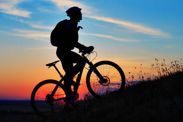 Silueta de un motorista y bicicleta en el fondo del cielo . — Foto de Stock