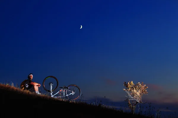 Man cyclist repairing a bike  against blue sky — Stock Photo, Image