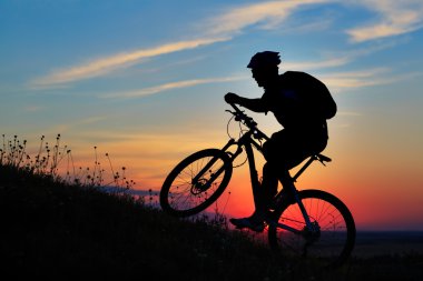 Silhouette bir motorcu ve gökyüzü arka plan üzerinde bisiklet.