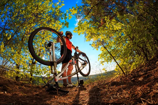 Человек-велосипедист чинит велосипед на фоне голубого неба — стоковое фото