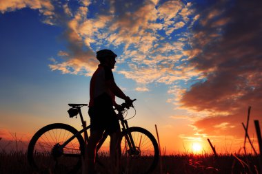 Silhouette bir motorcu ve gün batımı arka plan üzerinde bisiklet.